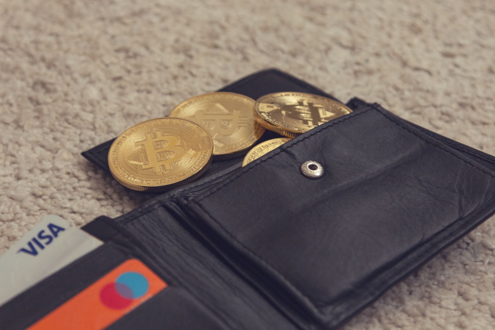 Close-up of bitcoins and credit cards inside a leather wallet, representing digital currency and finance.